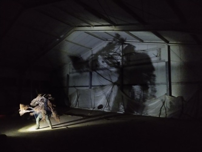 human in monster costume in big hall enlightened by small lamp